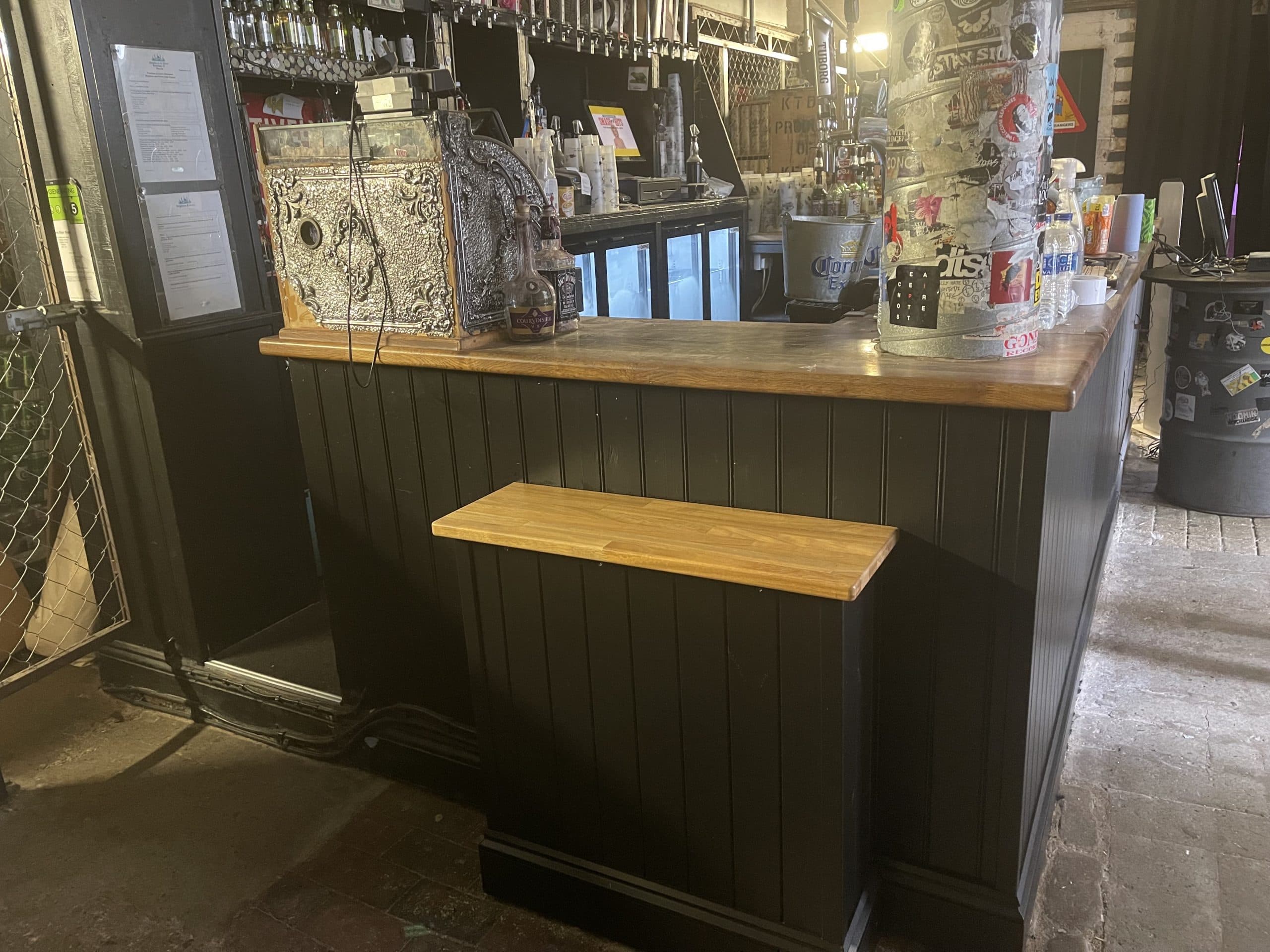 La barra del Green Door Store, con un tramo rebajado a la altura de una silla de ruedas, y el suelo de piedra desgastado delante.