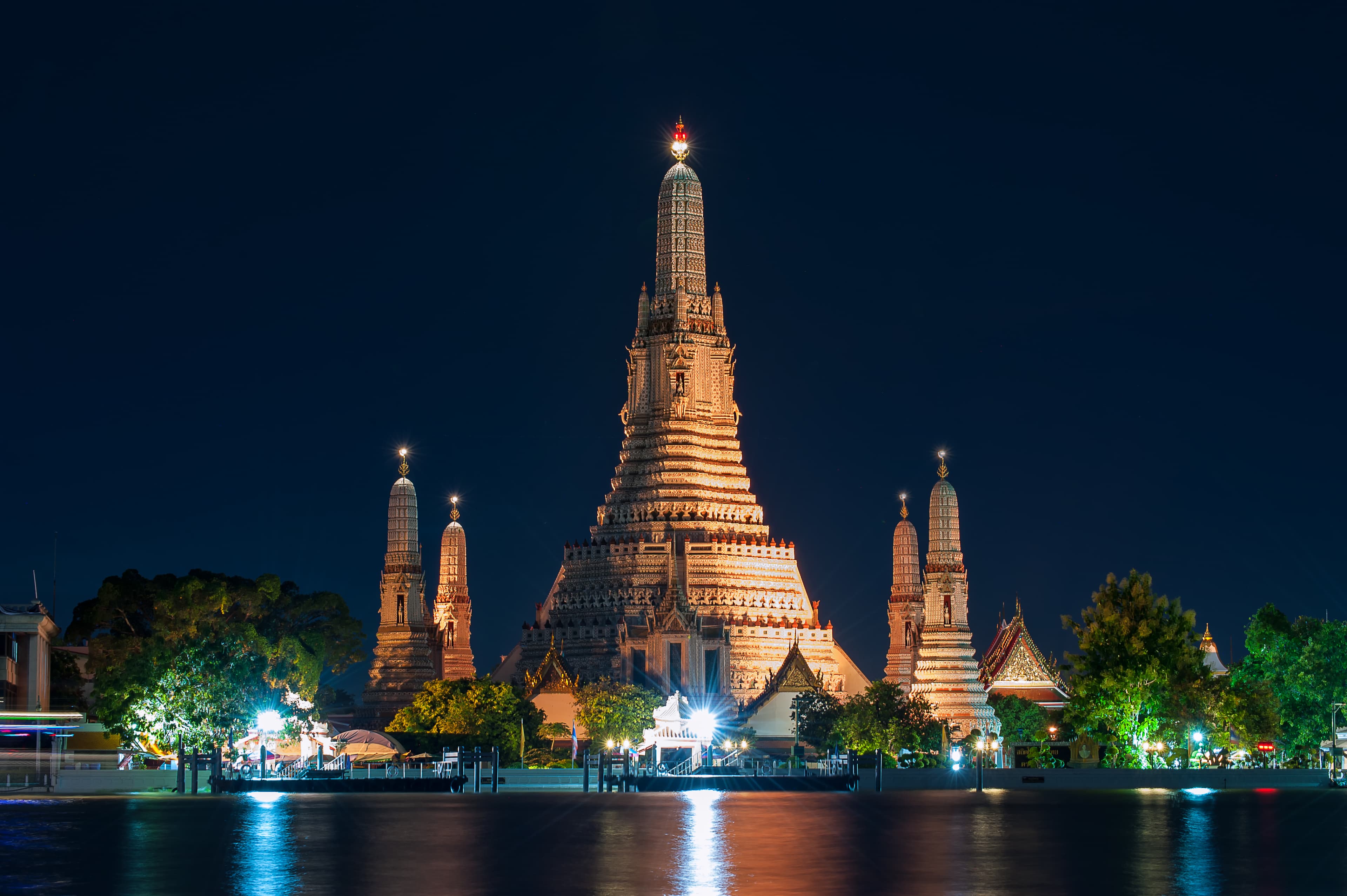 Wat Arun, the Temple of Dawn, lit at night on the Chao Phraya riverbank in Bangkok.