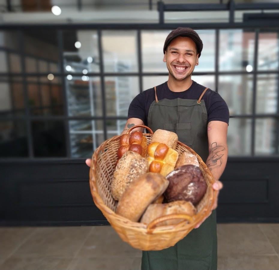 Un cesto di pane appena sfornato tra le mani di un dipendente di Art Bakery, São Carlos